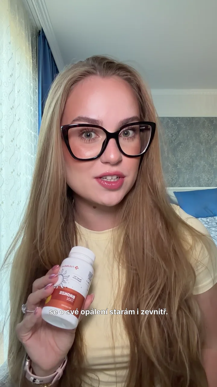 Sofiya holding a bottle of FutuNatura Bronze Tan capsules while speaking to camera